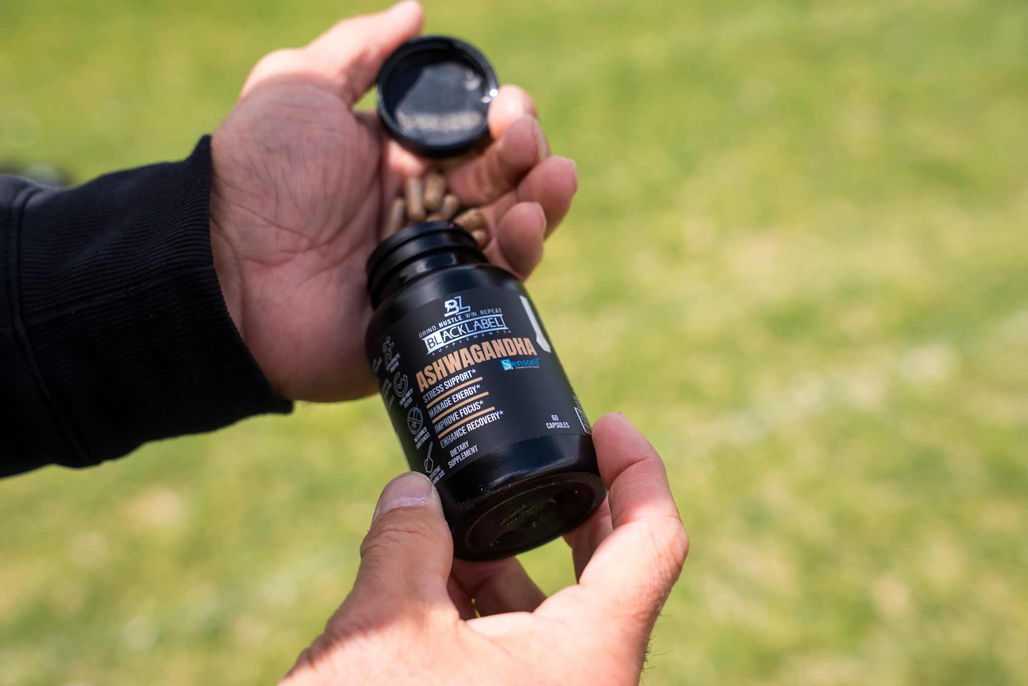 SENSORIL® ASHWAGANDHA supplement in a black bottle with an open cap and dark label featuring orange and white text