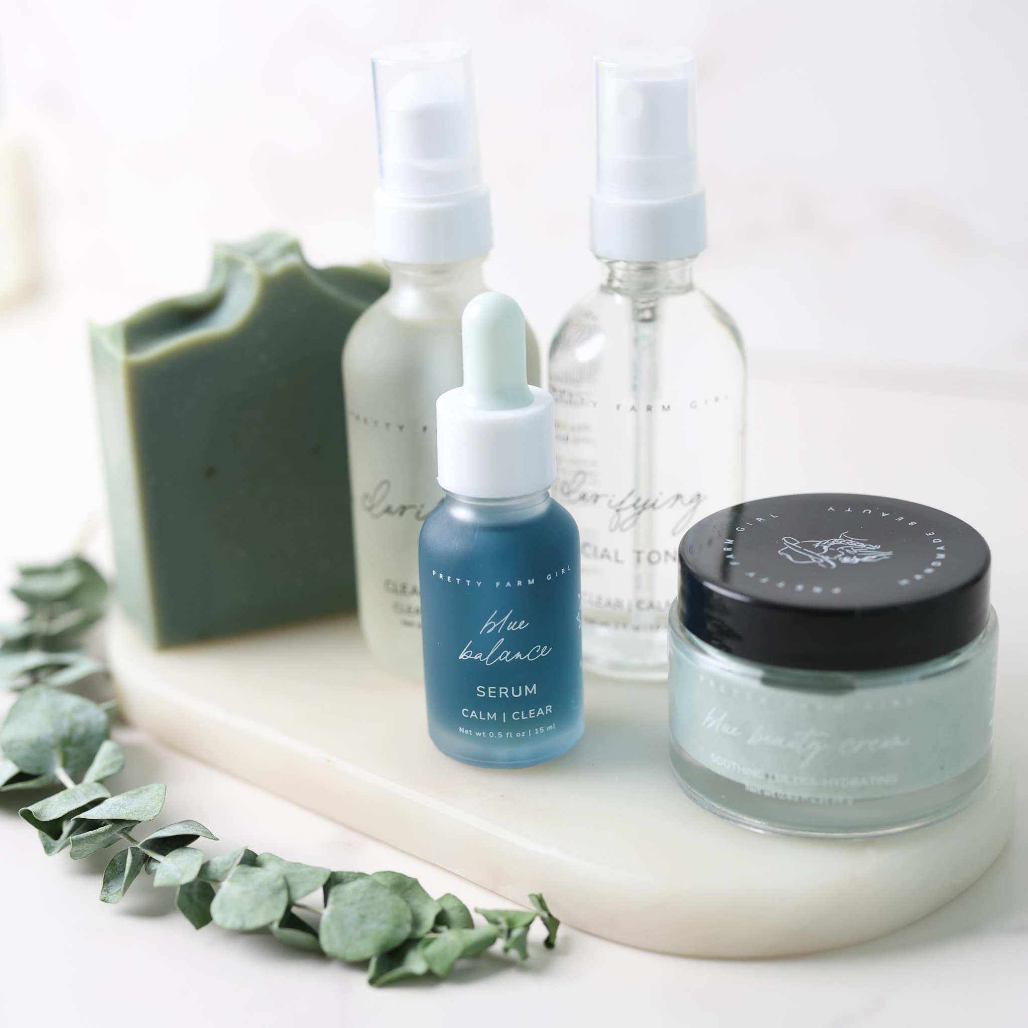 Skin Redness Skincare Routine Kit with blue serum, soap bar, cleansing oil, toner, and cream in glass containers