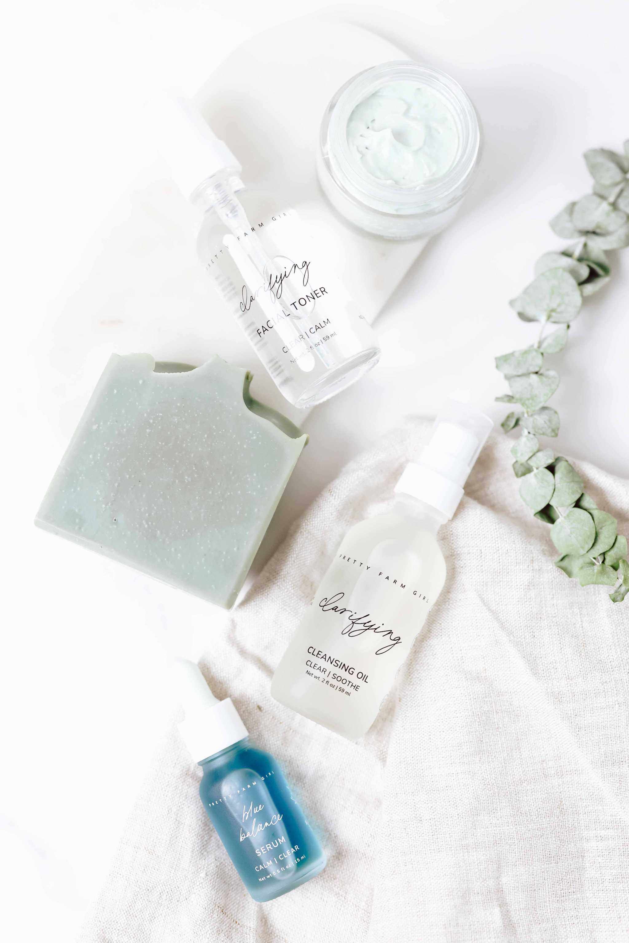 Skin Redness Skincare Routine Kit with blue soap bar, glass bottles, serum, cream jar, and toner spray
