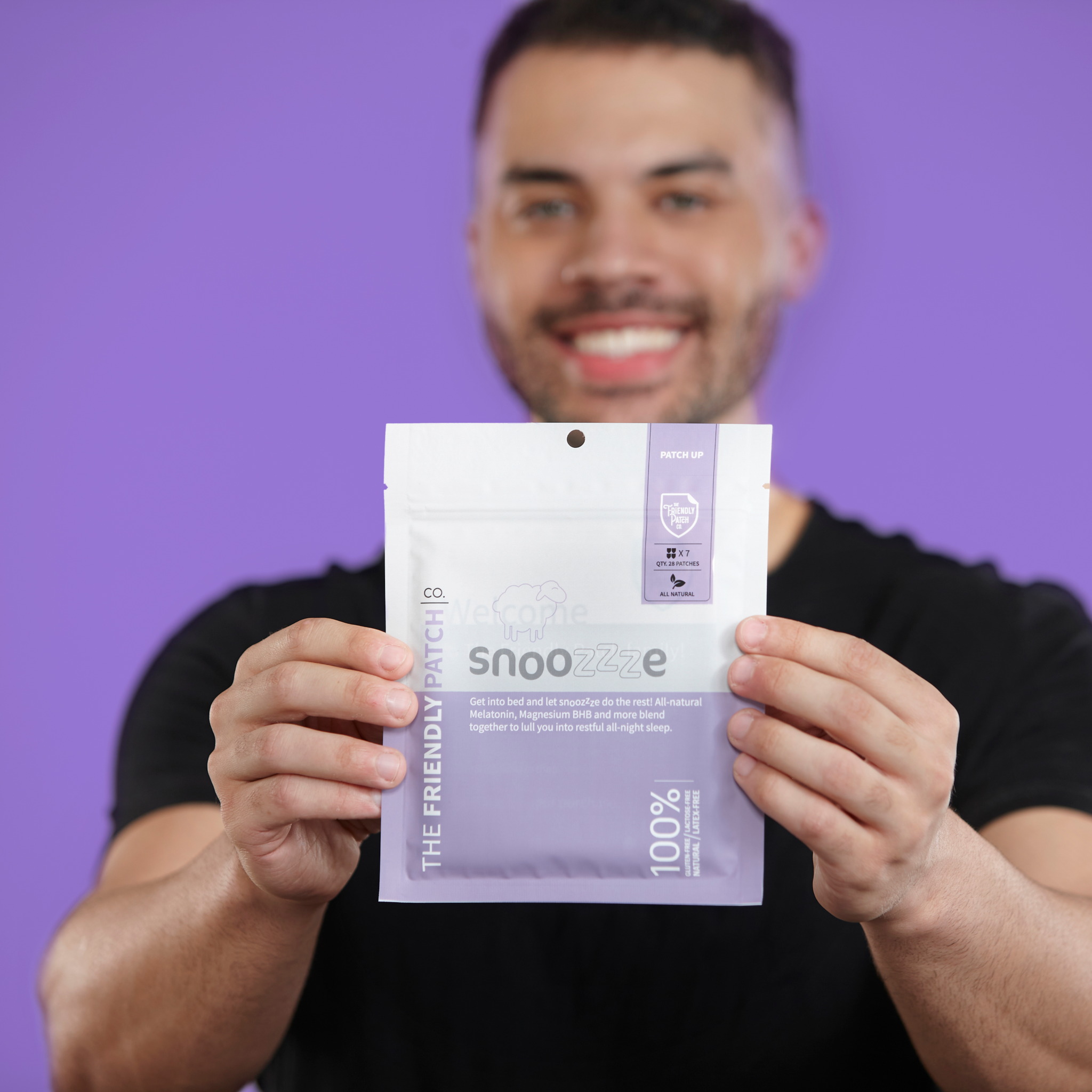 Sleep Patches in a white and lavender Snooze pouch with minimalist typography and a resealable top, held by a man