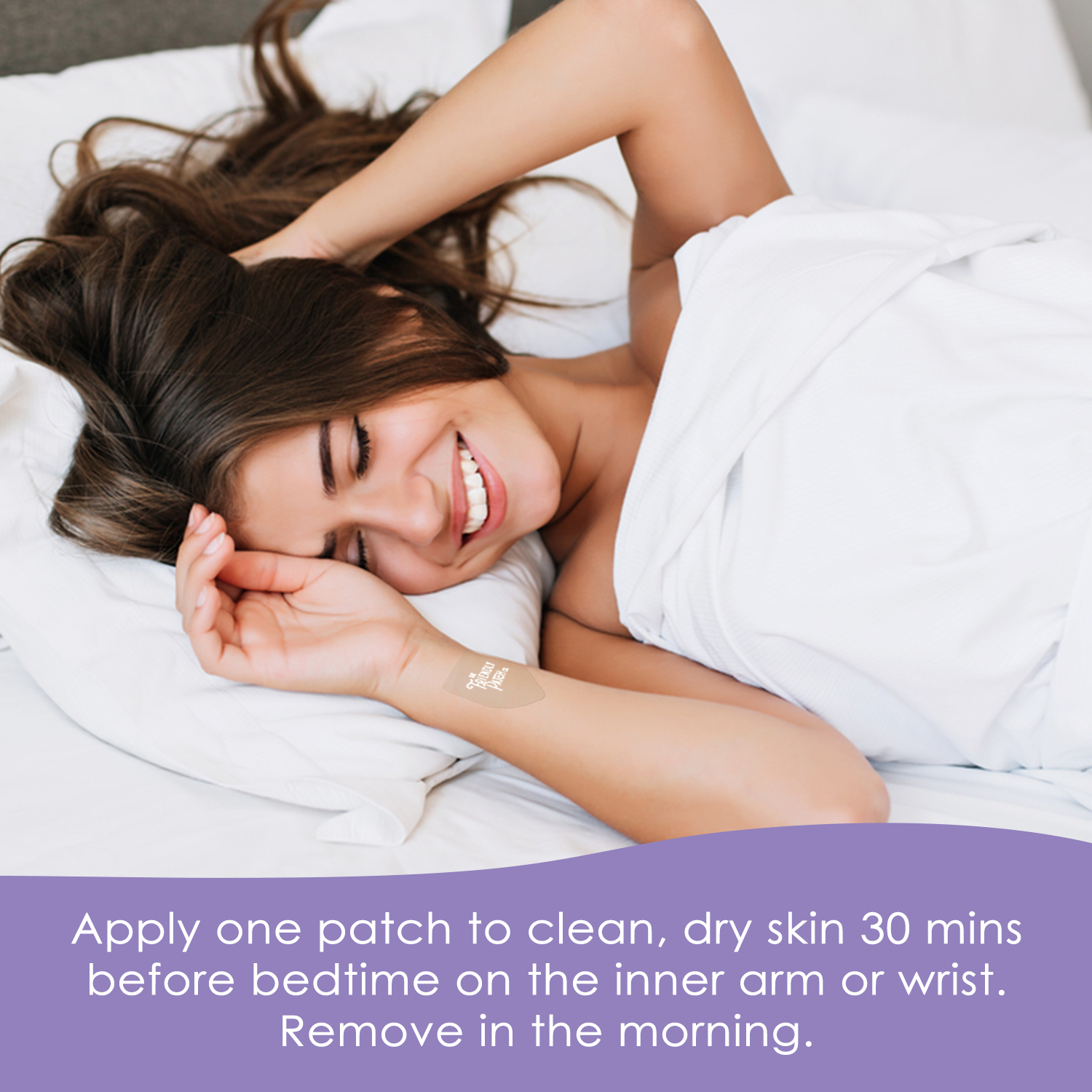 Woman lying in bed smiling with a white Snooze Melatonin Sleep Patch applied on her inner wrist, covered partially by white bedding