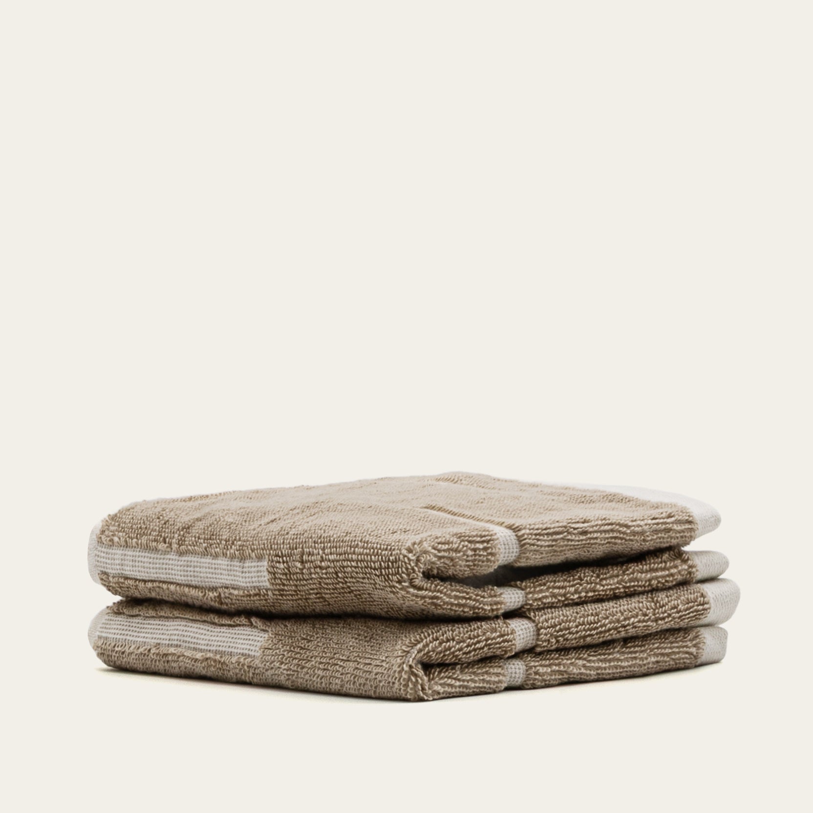 Sorrel Australian Cotton towels in warm sand beige, plush textured fabric with subtle white geometric stripe accents