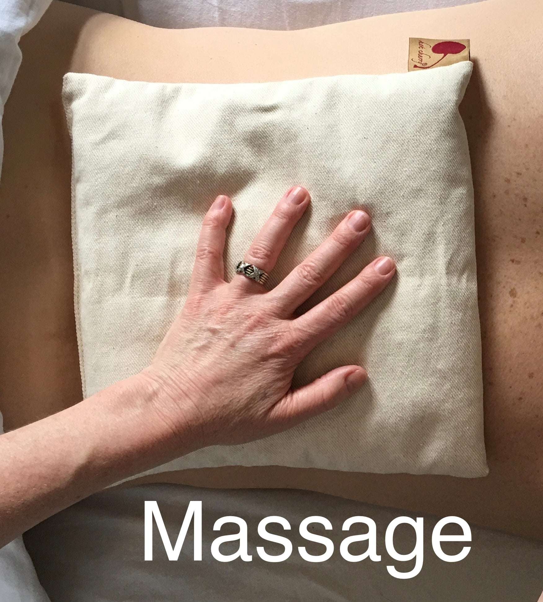Summer Stack square denim pillow in natural unbleached fabric, shown beneath a hand with a massage label