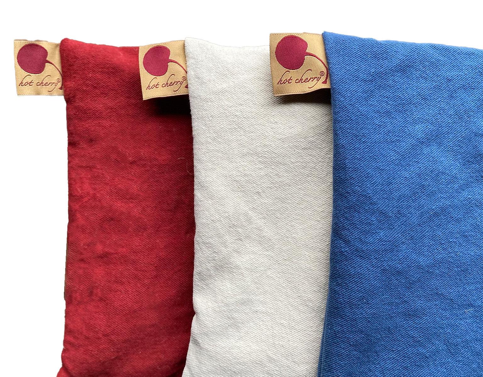 Summer Stack of three square denim pillows in red, natural and blue, with textured fabric and branded tags