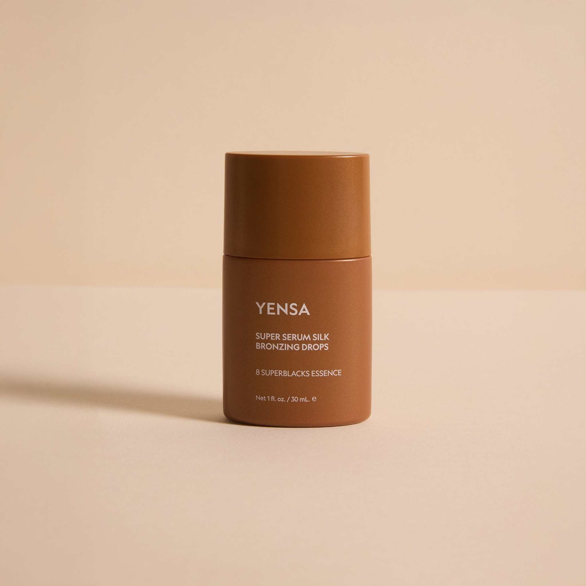 Super Serum Silk Bronzing Drops in a warm bronze-brown cylindrical bottle with a matching cap and white lettering