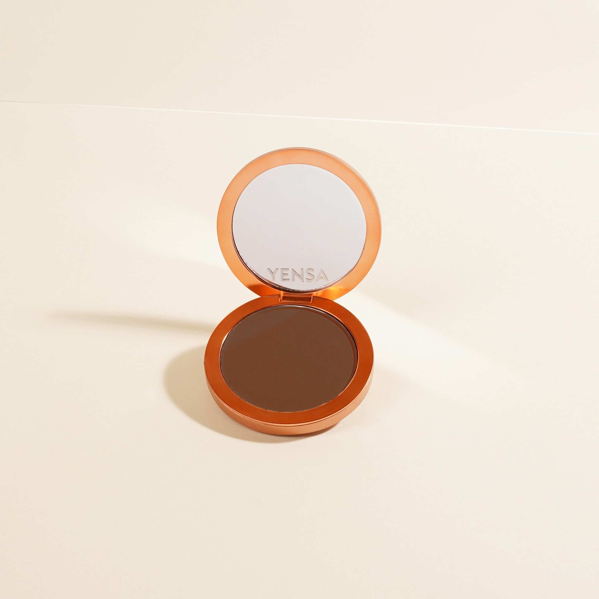Super Serum Silk Matte Foundation in a warm brown pressed powder compact with orange case and built-in mirror
