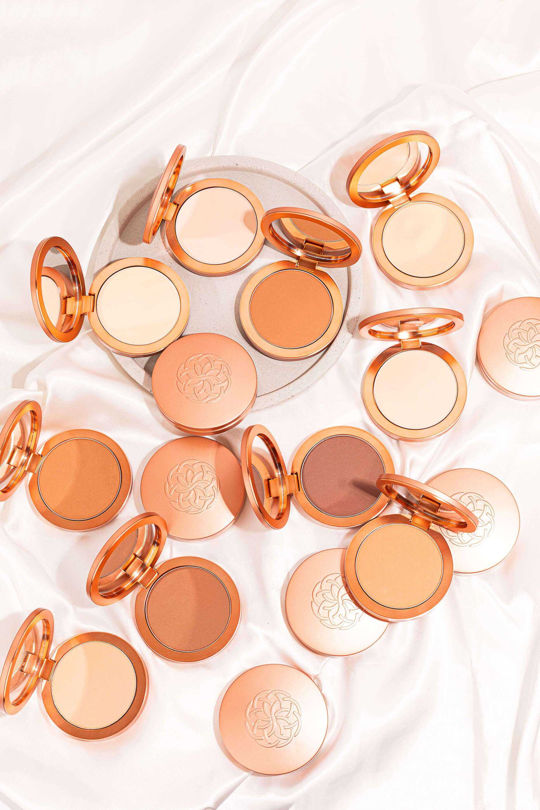 Super Serum Silk Matte Foundation compacts in peach and rose gold cases with warm beige, tan, and brown pressed powders