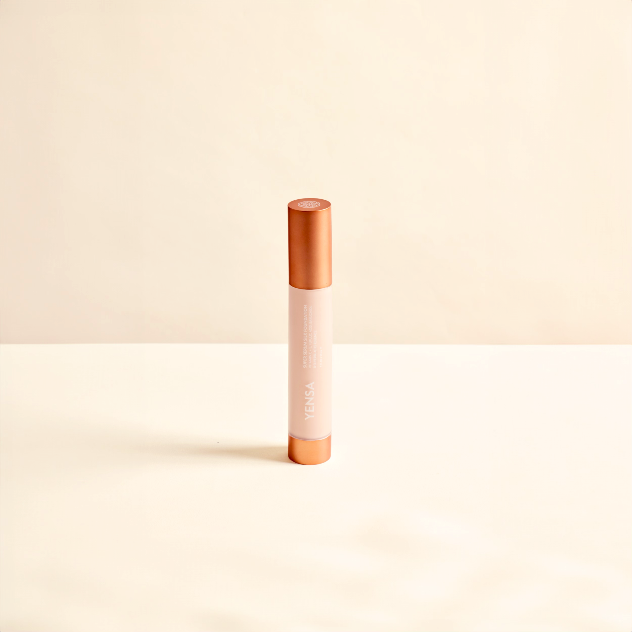 Super Serum Silk foundation in a slim pale pink tube with a copper-toned cap and matching base, featuring vertical white branding