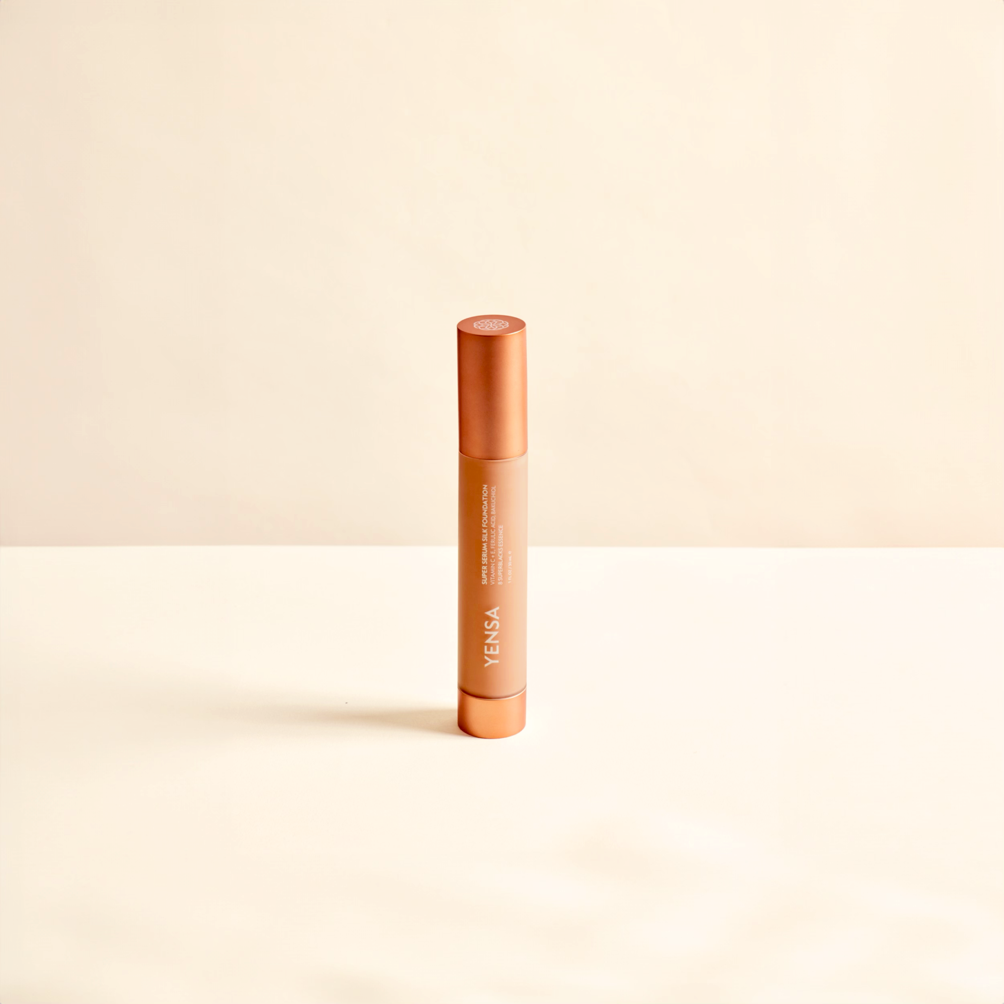 Super Serum Silk foundation in a slim peach-colored cylindrical bottle with a metallic copper cap and printed label
