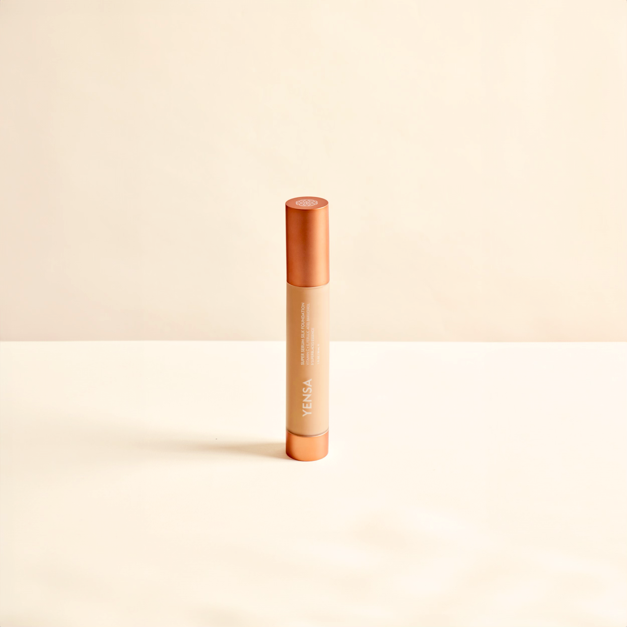 Foundation tube for Super Serum Silk, with a slim peach body and copper cap in a sleek cylindrical design
