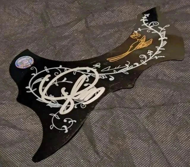 Taylor Swift Signed Pickguard in black with ornate white and gold artwork and a visible authenticity sticker