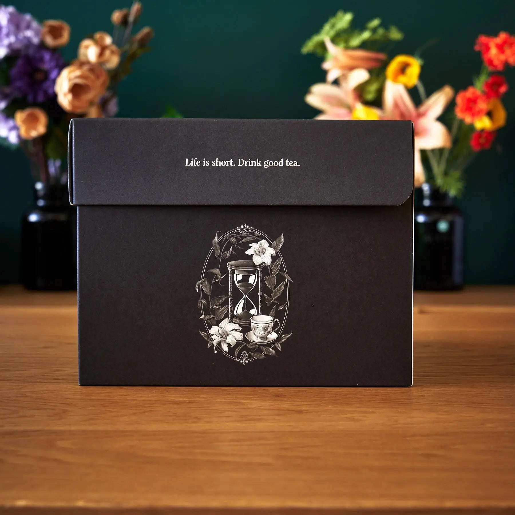 Tea Library - Deluxe black rectangular tea sampler box with white ornate teacup and hourglass illustration and printed slogan