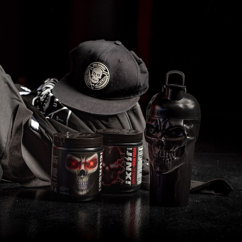 The Curse! Skull Shaker black plastic shaker bottle with skull design, screw-on lid beside black skull-themed nutrition tubs and cap