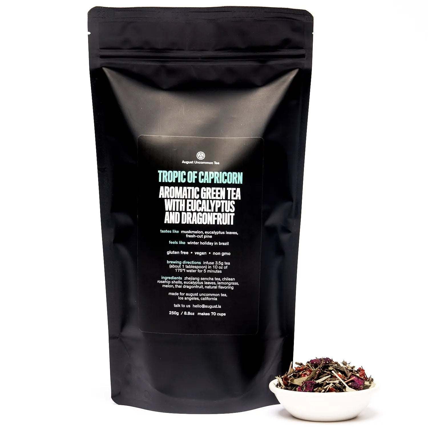 Tropic of Capricorn green tea in a black resealable pouch, with loose multicoloured tea leaves in a white bowl