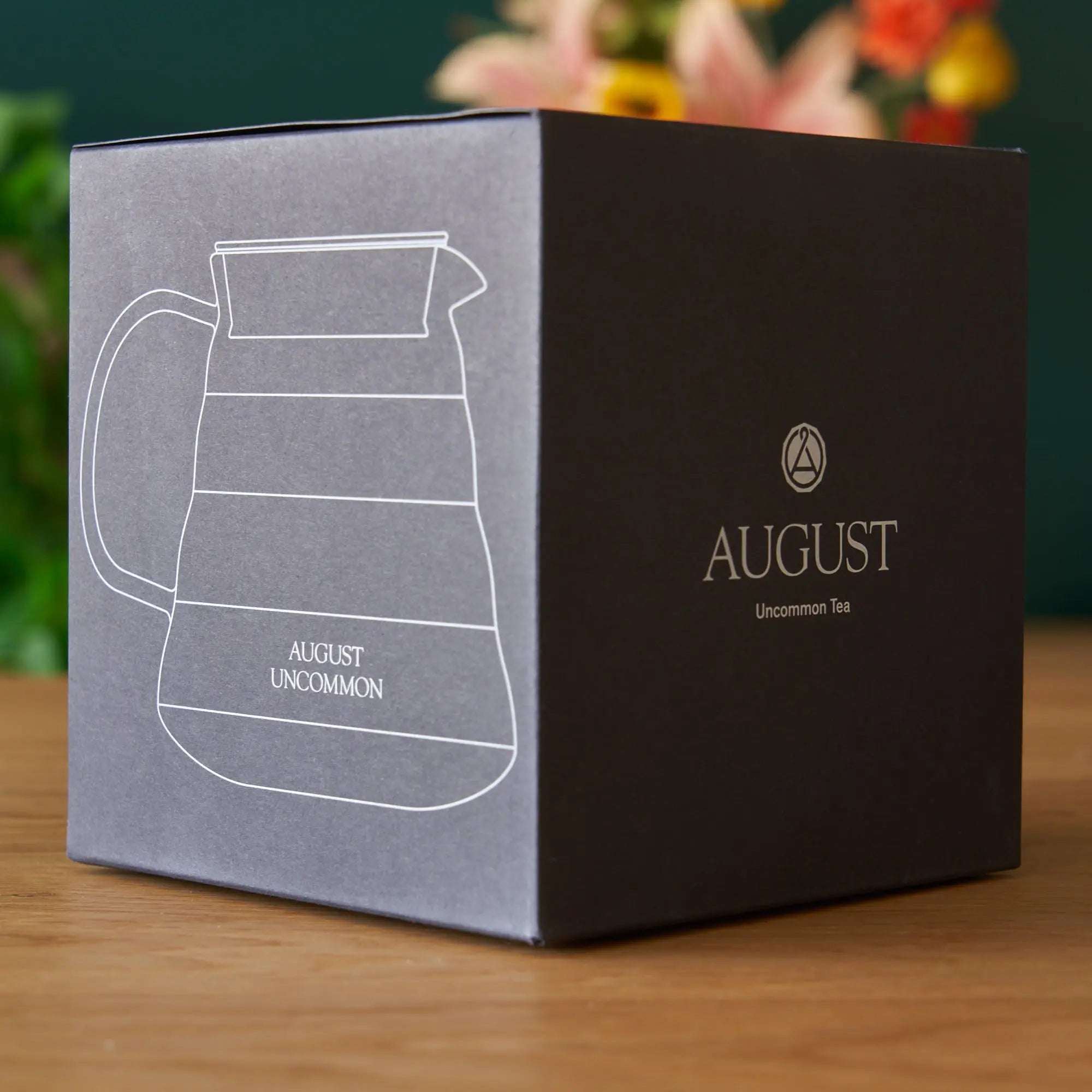 Two Cup Glass Teapot packaging in black and gray with a white outlined teapot illustration and August Uncommon Tea logo