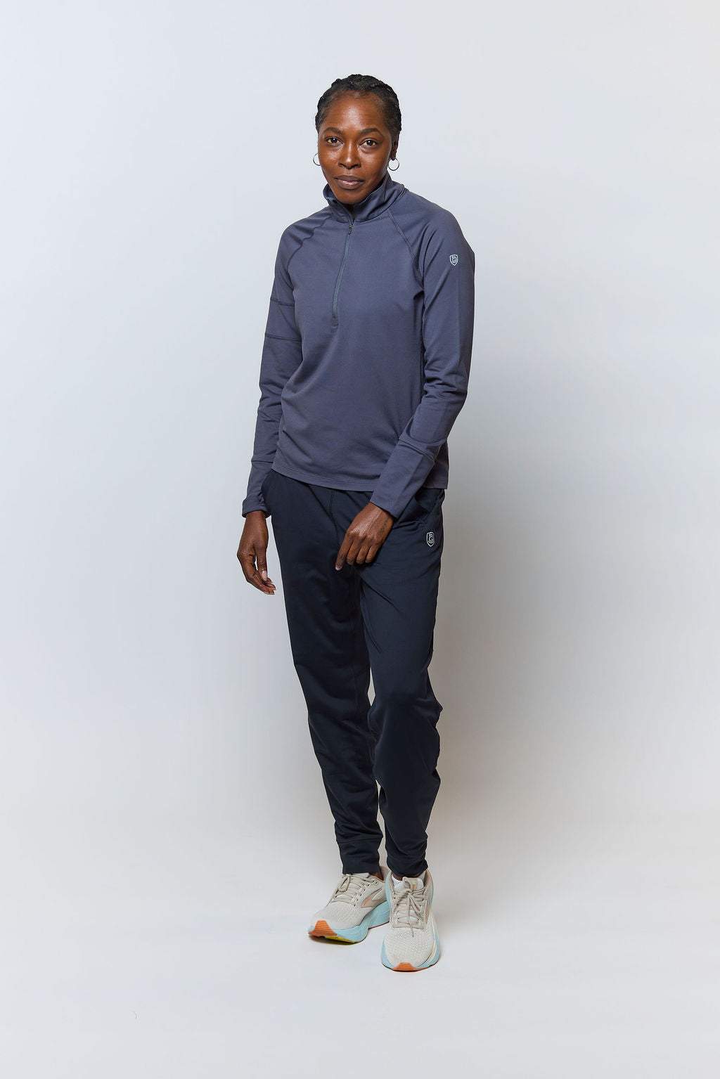 Valia Women's Black Jogger Pants in black with a slim athletic fit, tapered legs and ankle cuffs, worn with a navy pullover