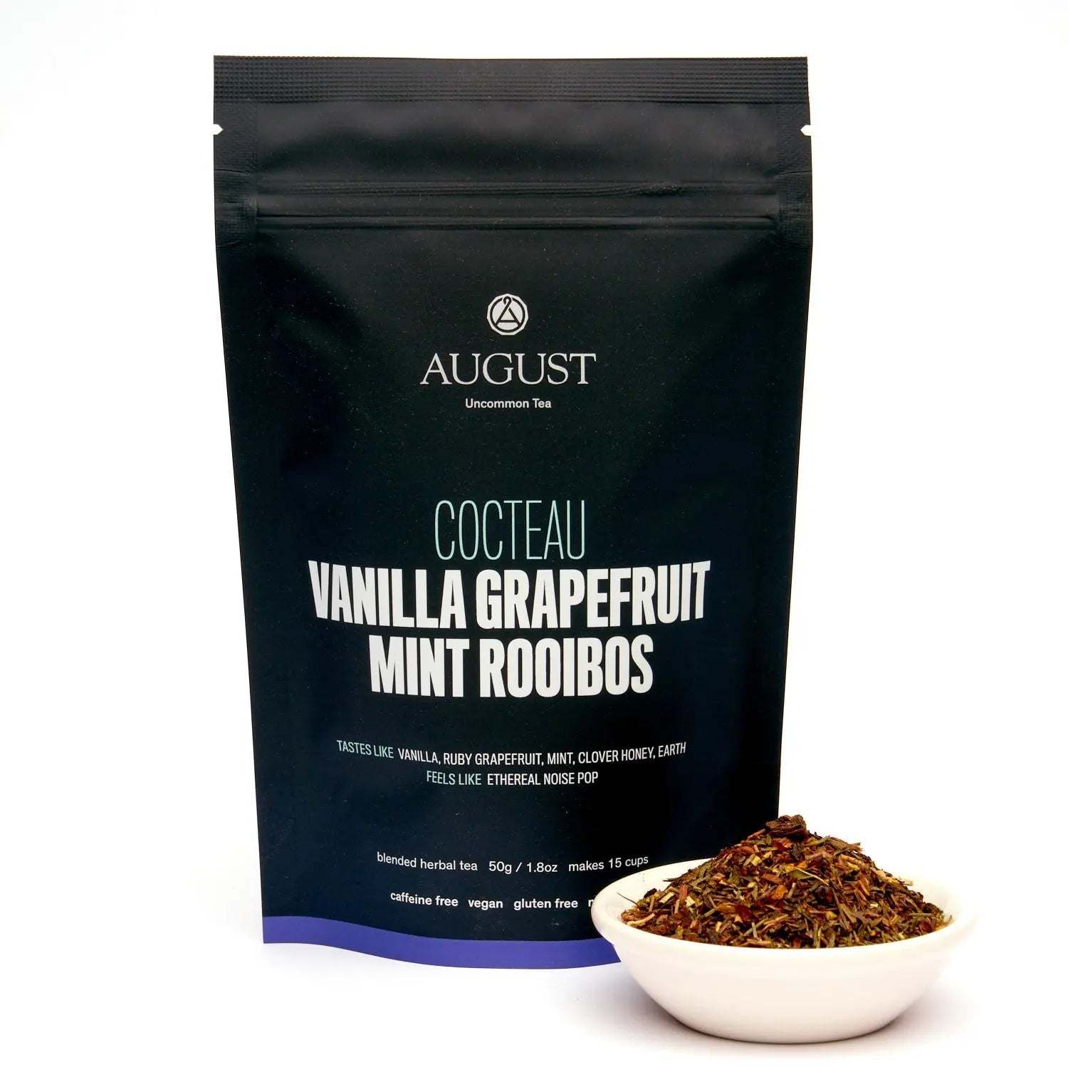 Vanilla Grapefruit Mint rooibos tea in a black August pouch beside a white bowl of loose herbal tea