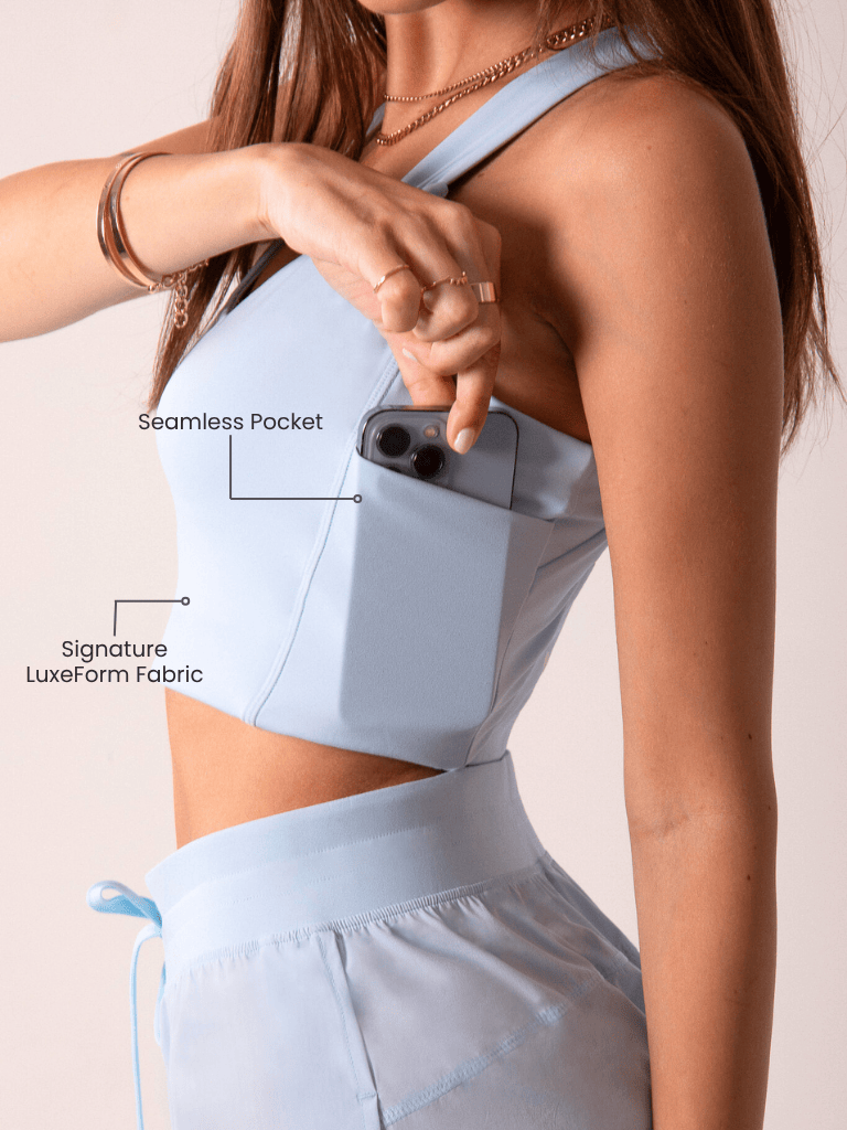 Women's Workout Tank Top in pale blue smooth fabric, showing a seamless side pocket holding a phone and a wide strap.